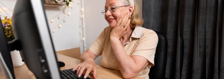 Older woman in home office using desktop computer