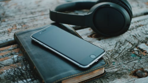 Book and phone next to audio headphones