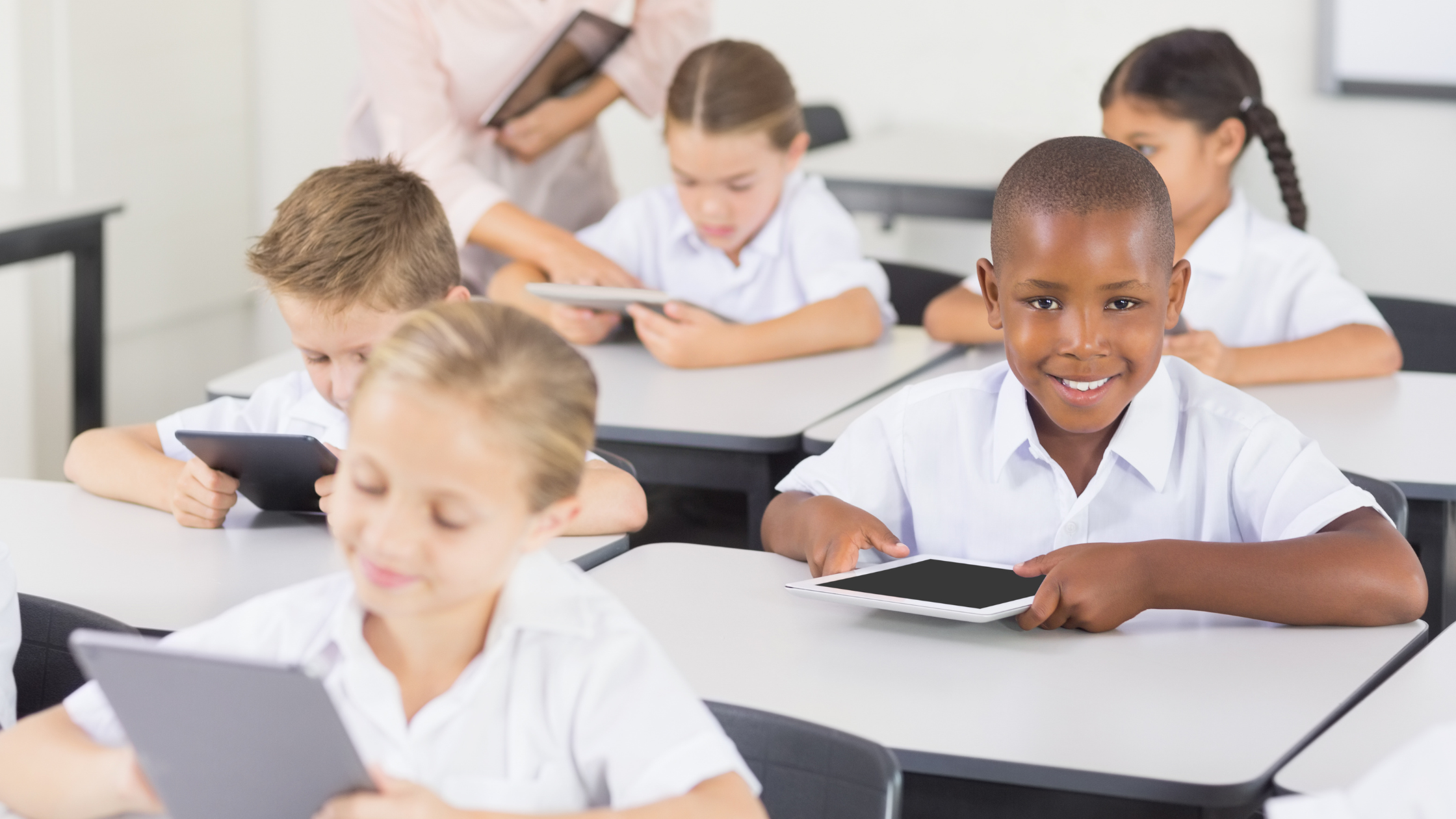 Happy student reading on a tablet in class 