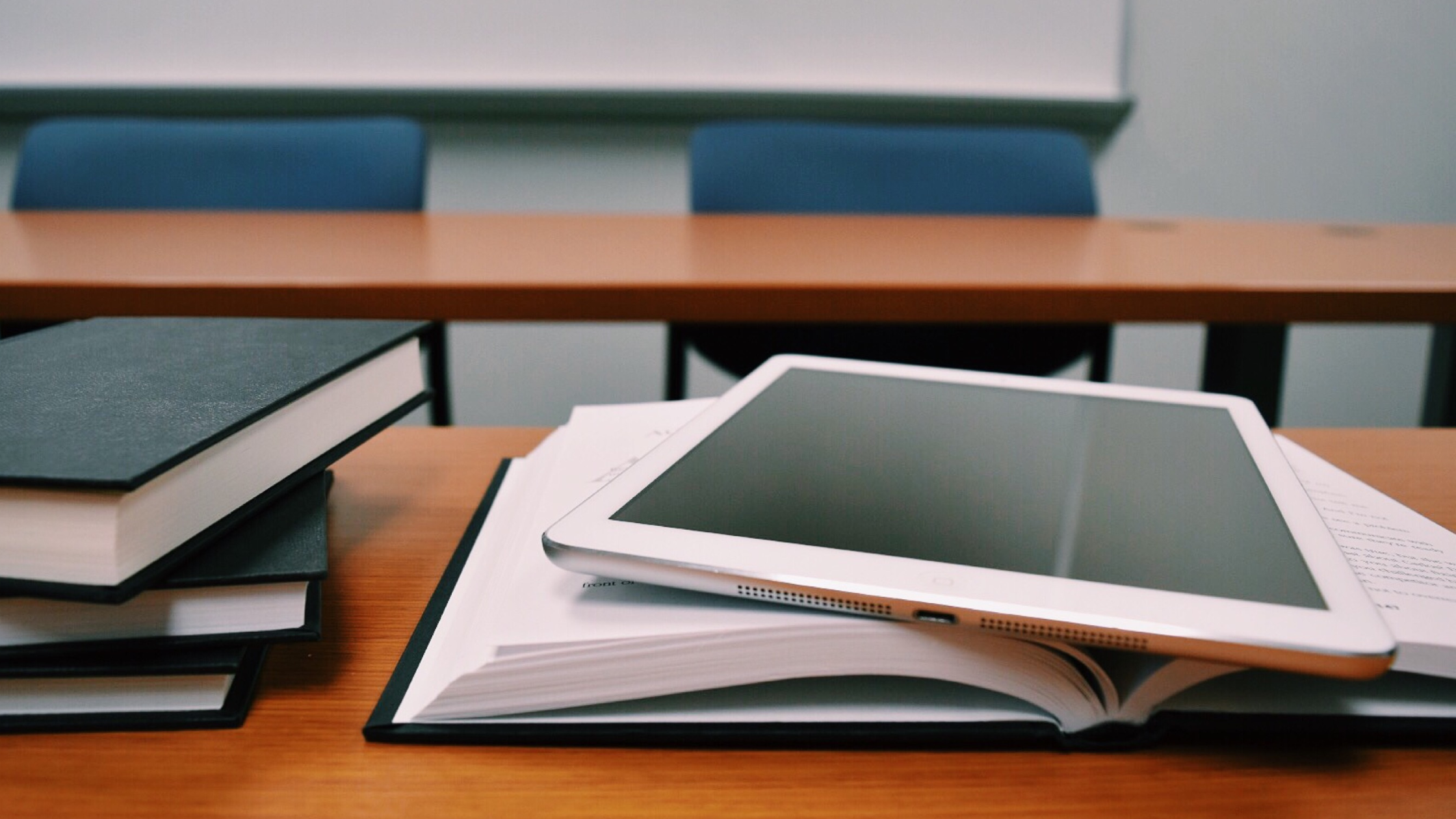 Pile of books and a computer tablet on a school desk