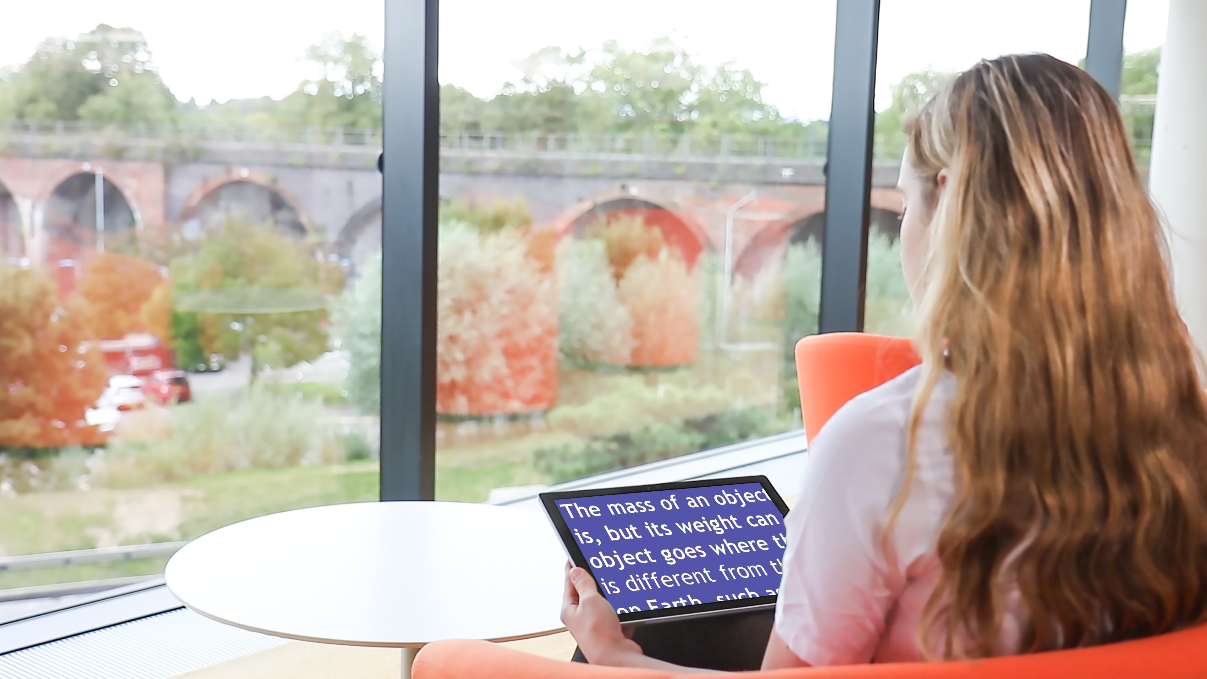 Woman reading on a tablet screen in front of a window