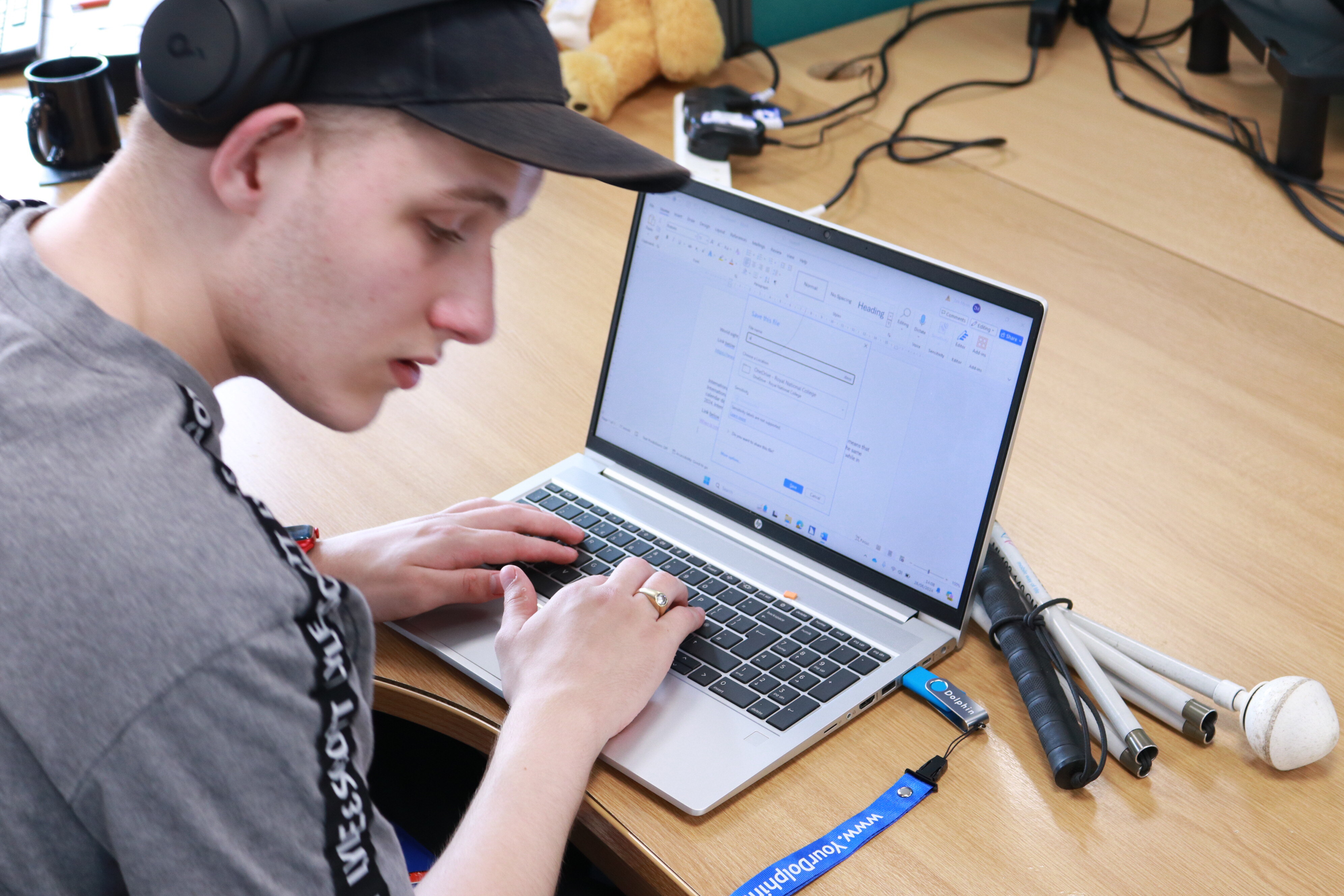 Student Zak is typing on a laptop in the Dolphin office.