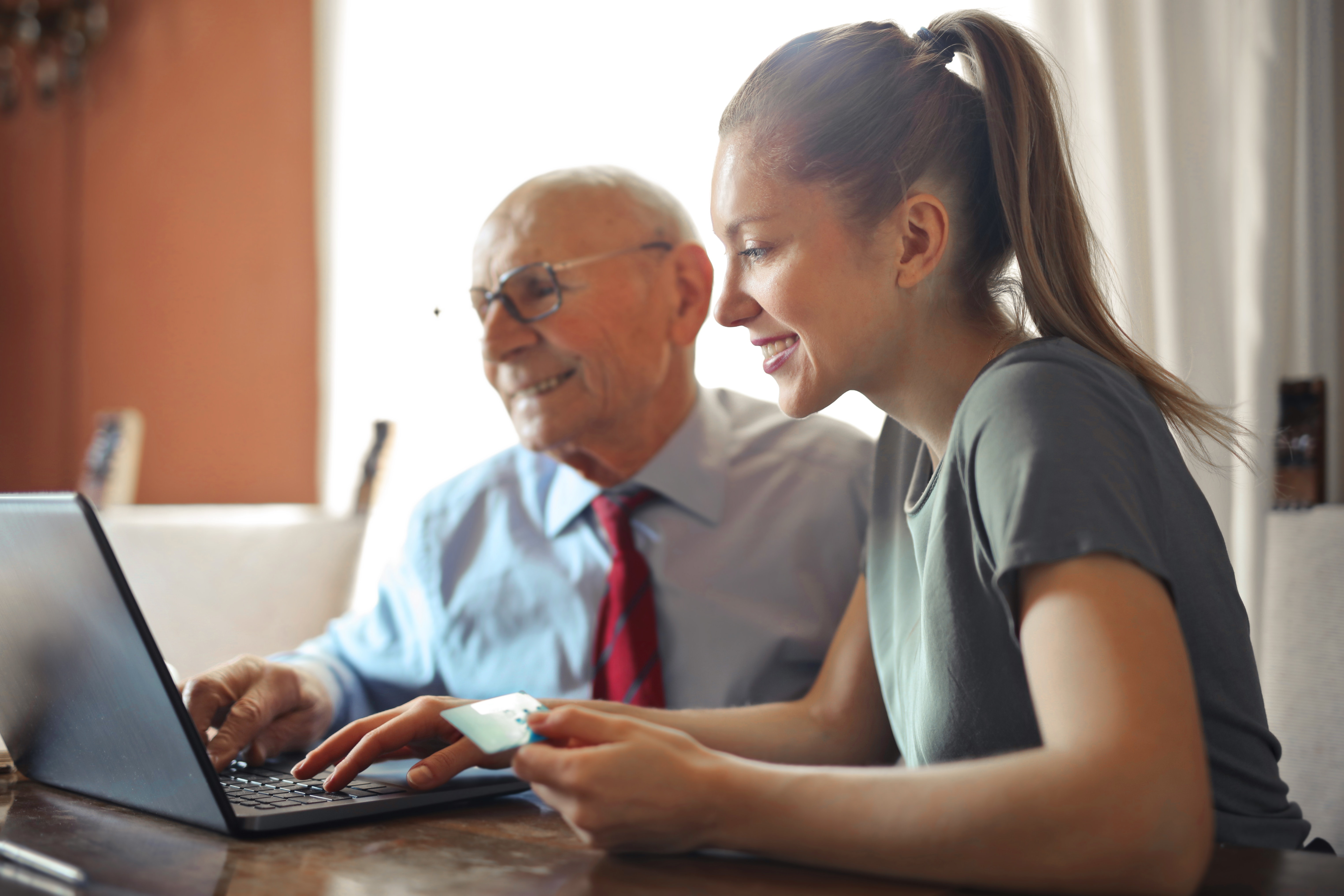 lady showing elderly man how to use laptop