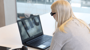 Student Charlotte is sitting at a desk with an open laptop in front of her. 