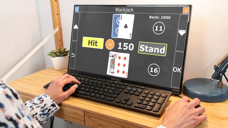 Image shows a desktop computer screen, with the hands of a person playing Blackjack on GuideConnect on the keyboard