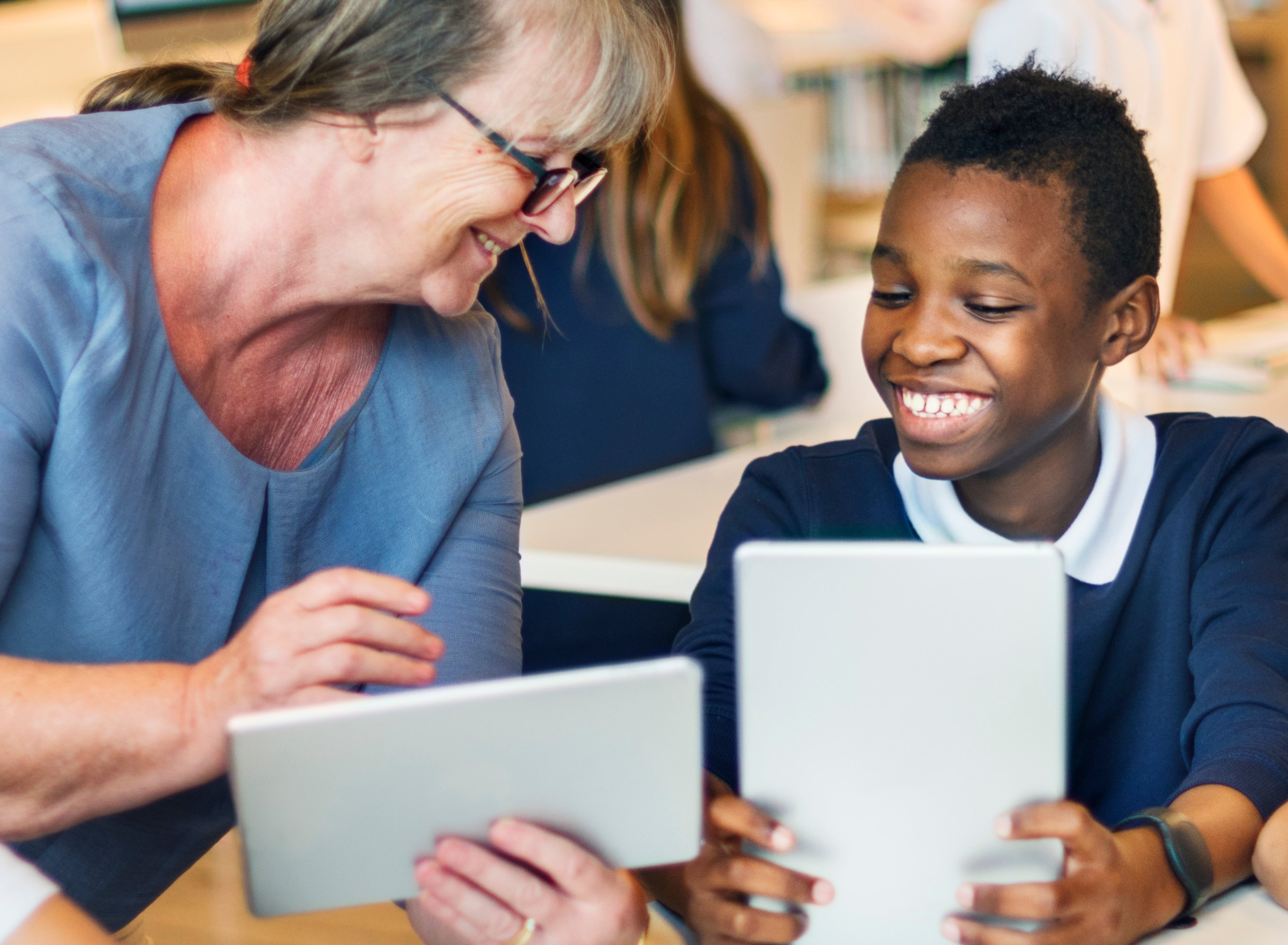 TA and student smiling as they read on a tablet