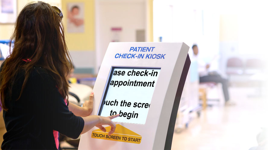 A woman is standing in front of a patient self-service check-in kiosk and the text is magnified.