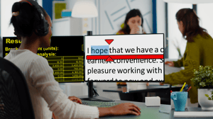Woman in an office wearing headphones sat in front of two monitors reading an email using SuperNova magnification