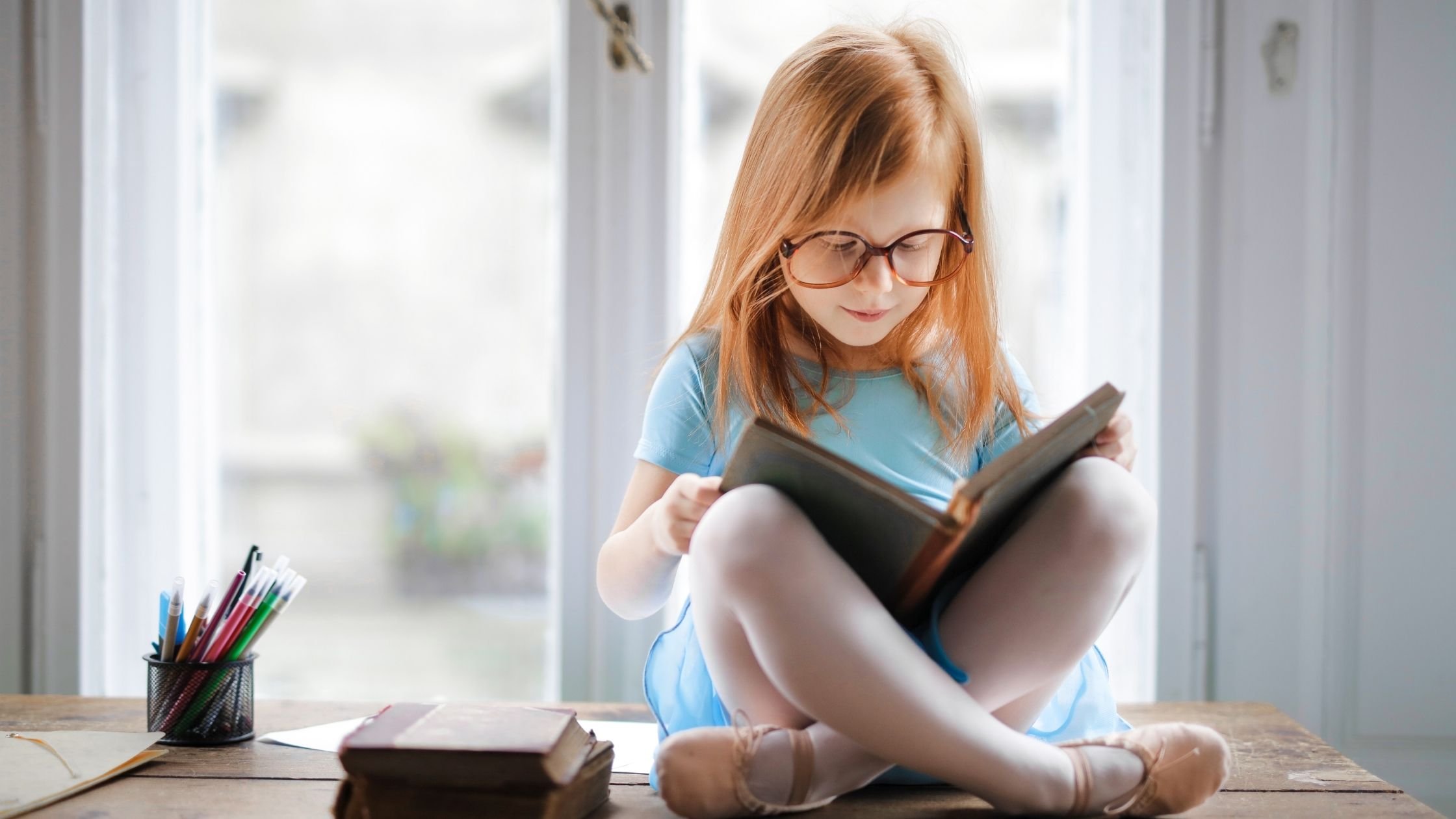 child sitting cross legged reading a book